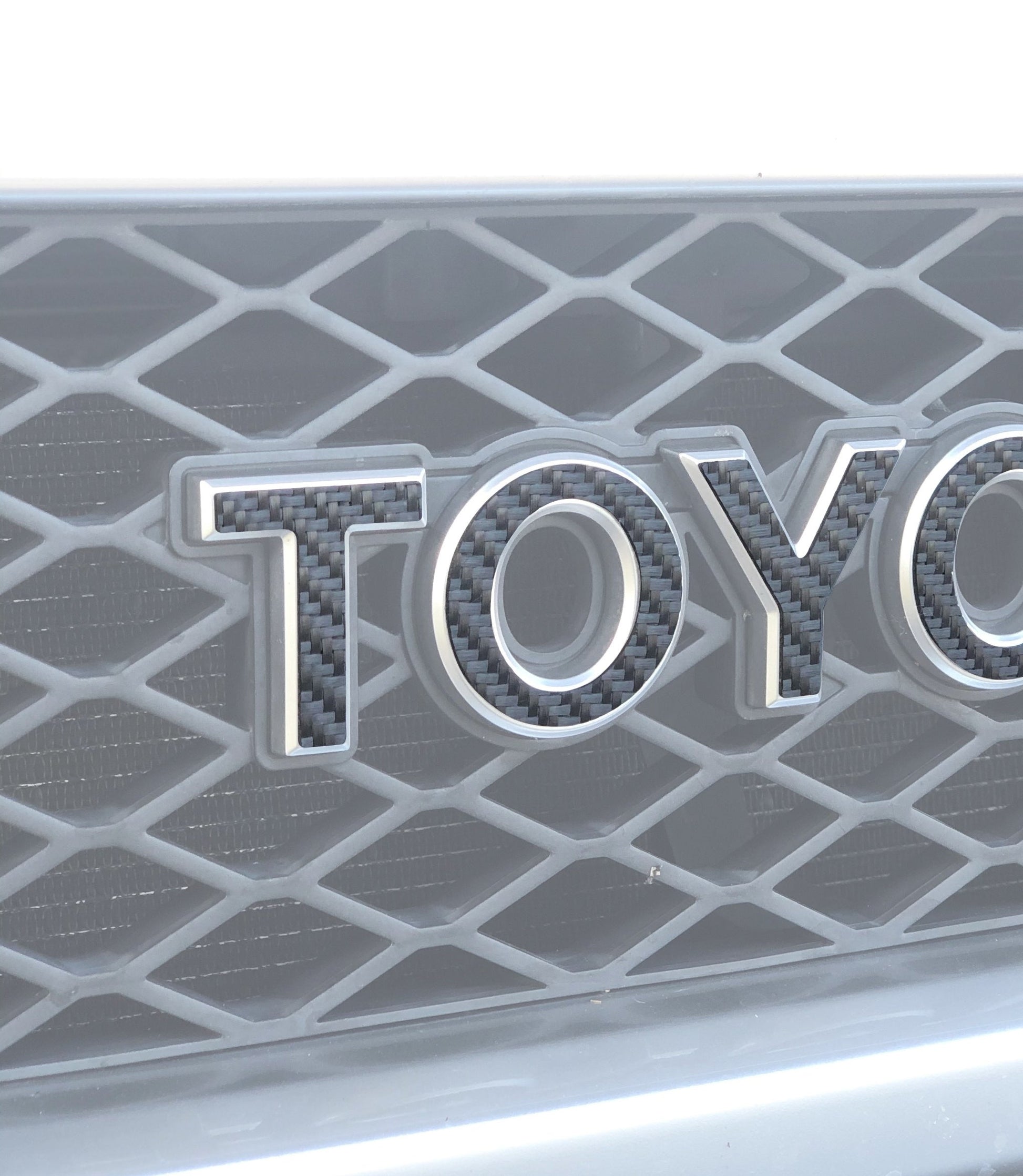 Toyota logo on a car grille with a diamond pattern