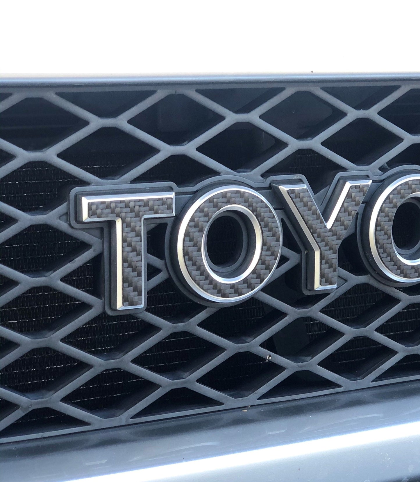 Close-up of a Toyota logo on a car grille with a black honeycomb pattern.