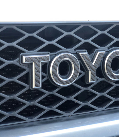 Close-up of a Toyota logo on a car grille with a black honeycomb pattern.